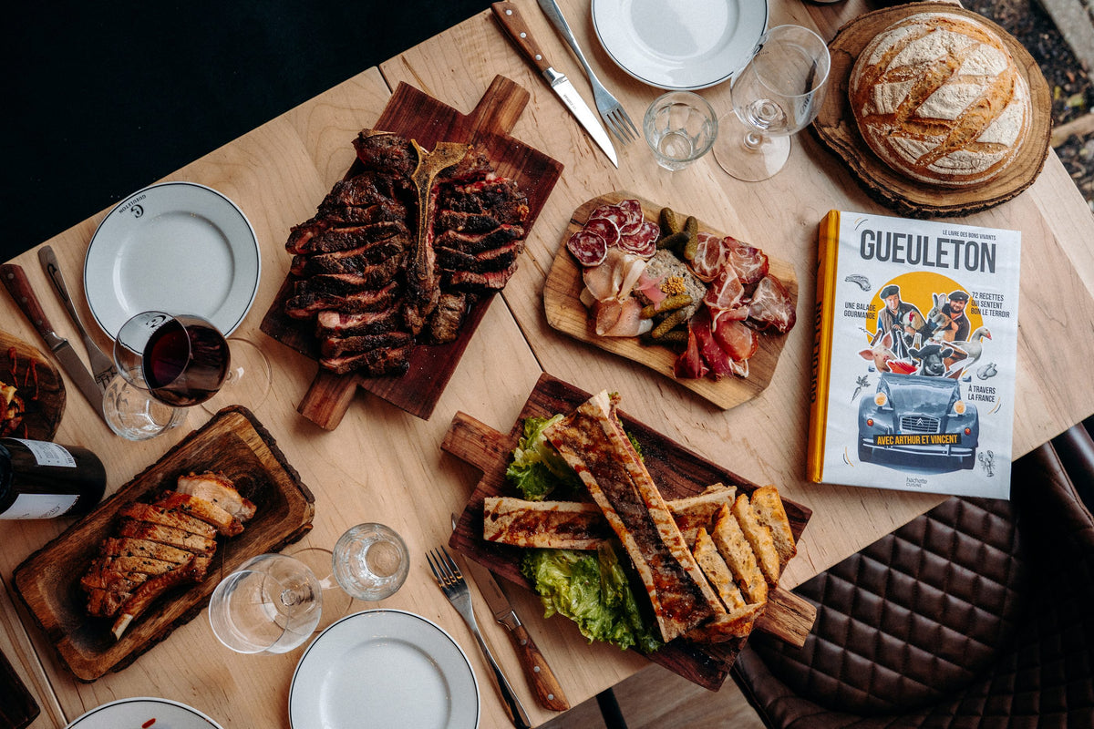 Table dressée vue de haut au restaurant Gueuleton Montréal : côte de bœuf, charcuteries, pain et vin rouge