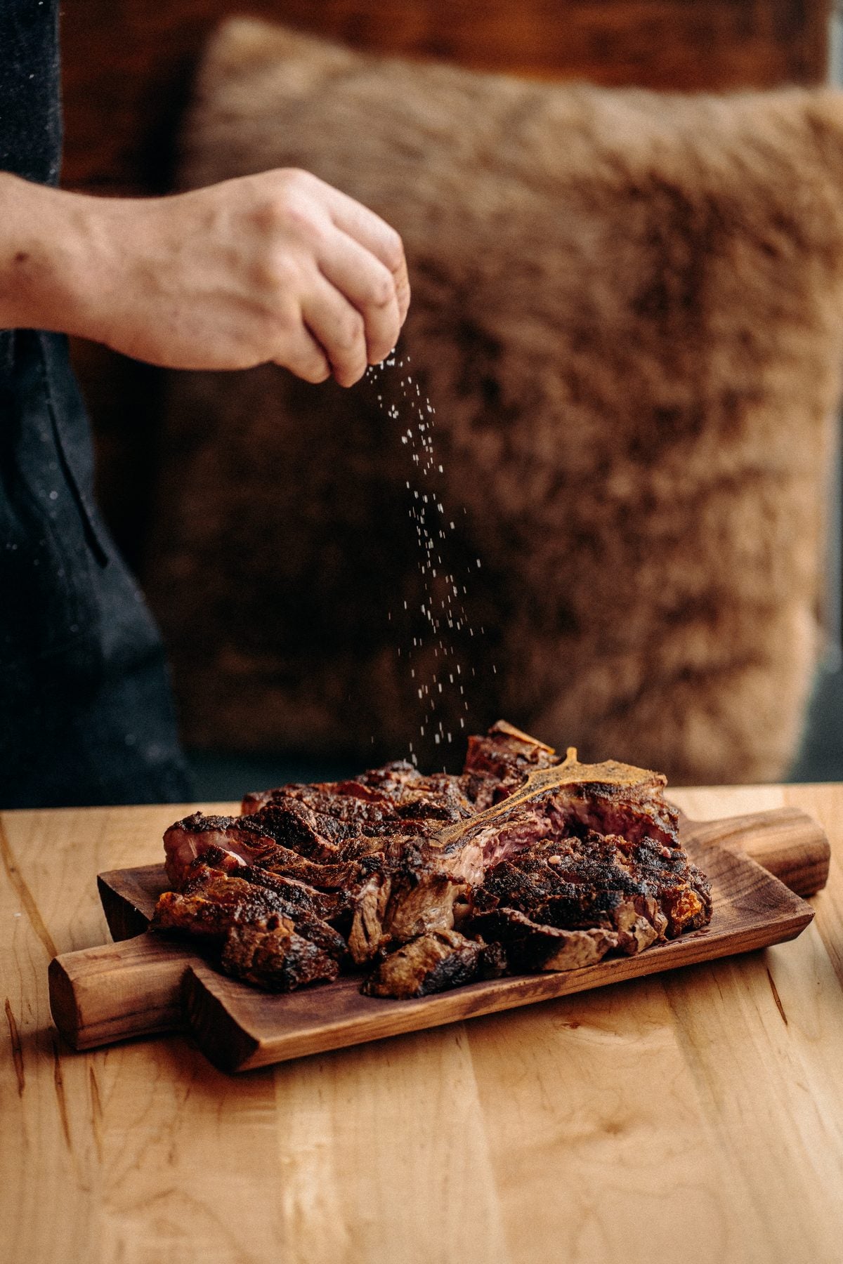 Le chef du Gueuleton Montréal assaisonne une pièce de viande en cuisine
